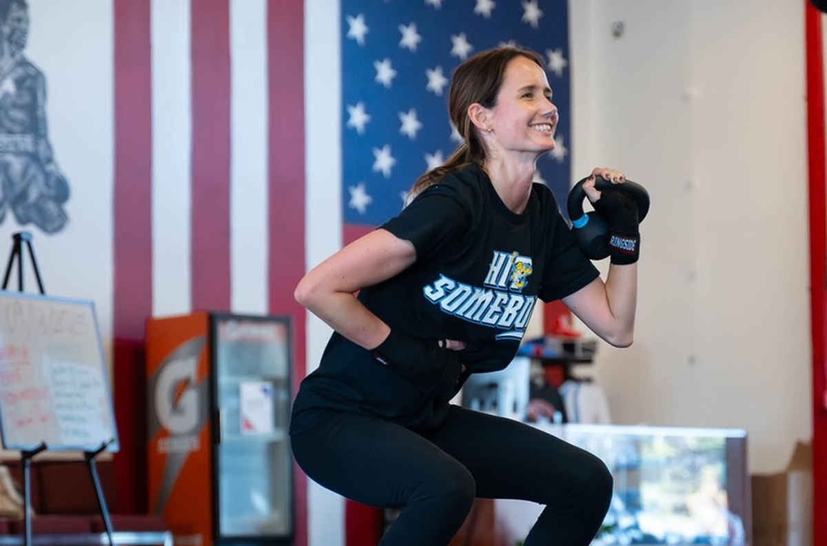 A member squatting with a kettlebell on the turf at Fortivus
